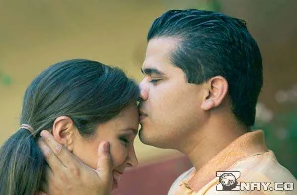 Мужчина целует свою девушку в лоб