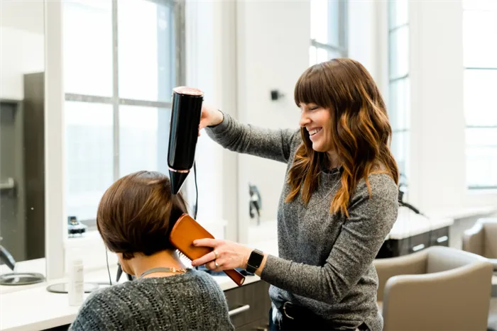 Девушке с тонкими волосами делают прическу в парикмахерской