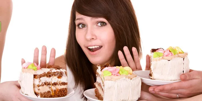 Молодая женщина отказывается брать торт.