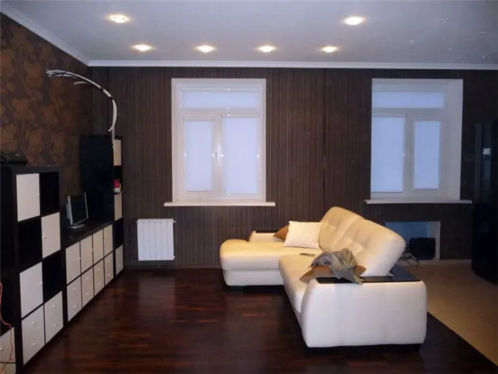 Фото: remont-f.ruТемный дизайн гостиной разбавлен модульными стенами с белыми диванами и белыми фасадами.