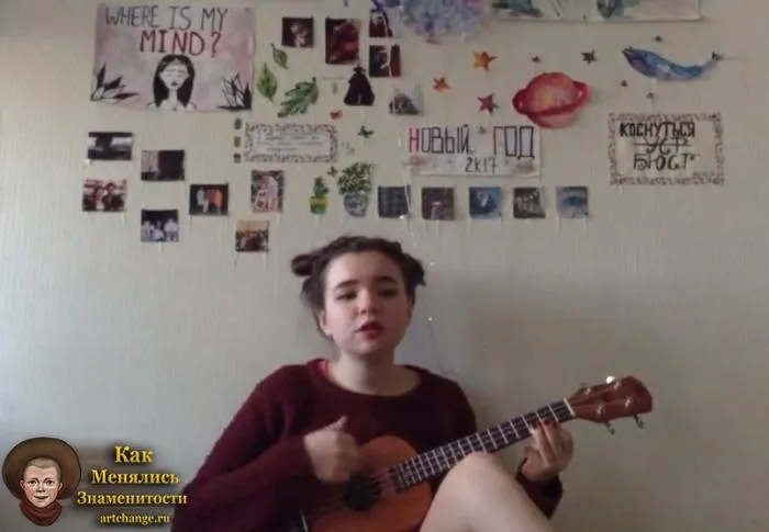 Алена Швец играет на гитаре дома у себя в комнате, на фоне рисунков