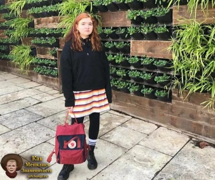 Алена Швец с рюкзаком на фоне стены с травой